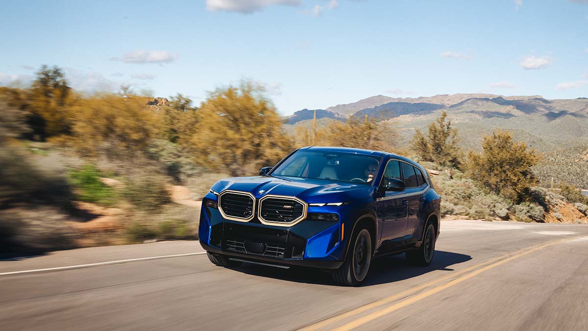 Blue BMW iXM Exterior Front Driving in Desert Mountain Range